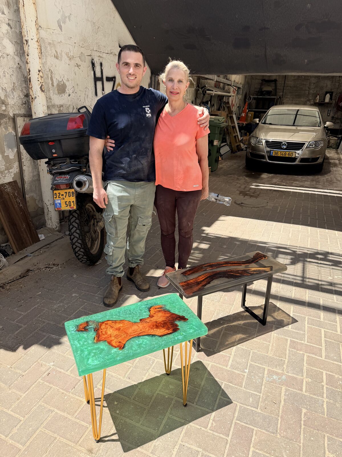 זוג משתתפים מציגים שולחן שיצרו בסדנת אפוקסי